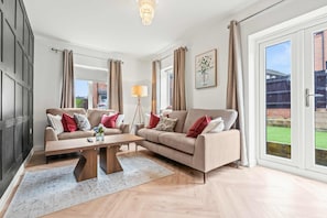 A modern living room with two sofas, a coffee table, and a floor lamp. - The Harmony House at Honor Estate (Telford)