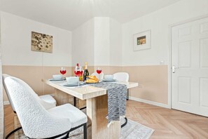 A dining area with a table set for two, featuring a bottle of wine, glasses, and a croissant. - The Harmony House at Honor Estate (Telford)