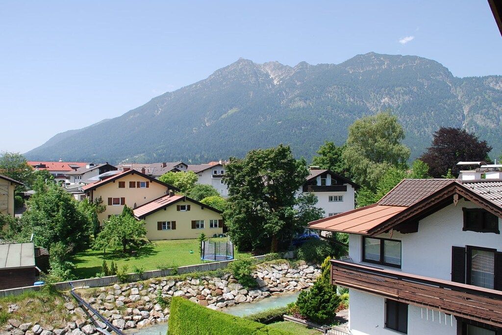 A residential area with houses, a small stream, and mountains in the background.