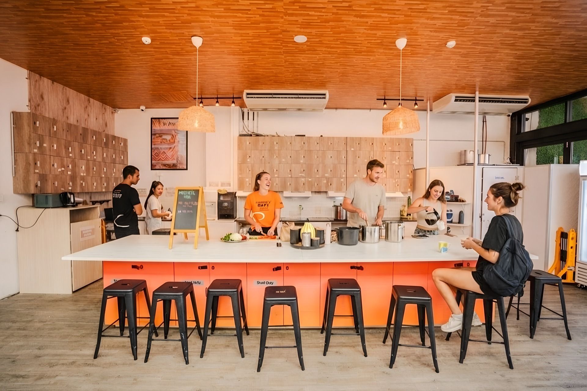 Una cocina moderna con armarios de madera, una isla central con taburetes e iluminación colgante.