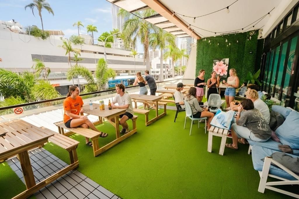 An outdoor seating area with tables and chairs, surrounded by greenery and a view of the cityscape.