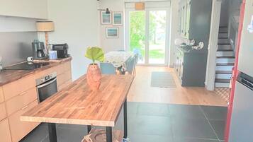 Una cocina con una mesa de madera, un florero con una planta y un comedor con sillas.
