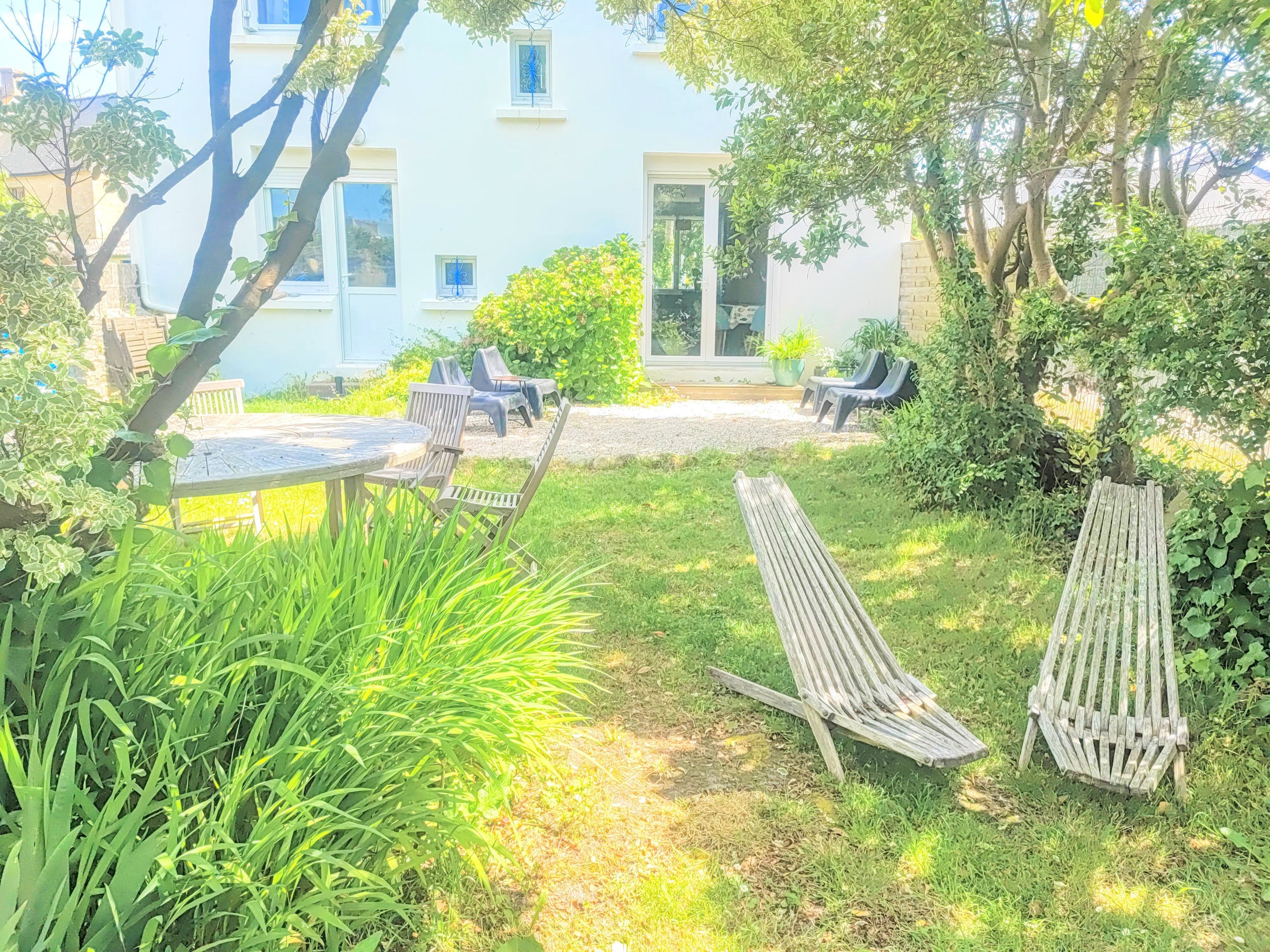 Un jardín con una mesa y sillas, un banco de madera y un edificio al fondo.