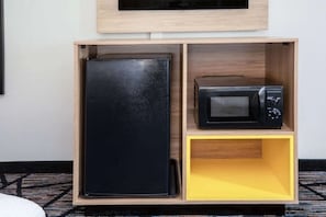 Un armari de fusta amb un frigorífic negre i un microones a la part superior.