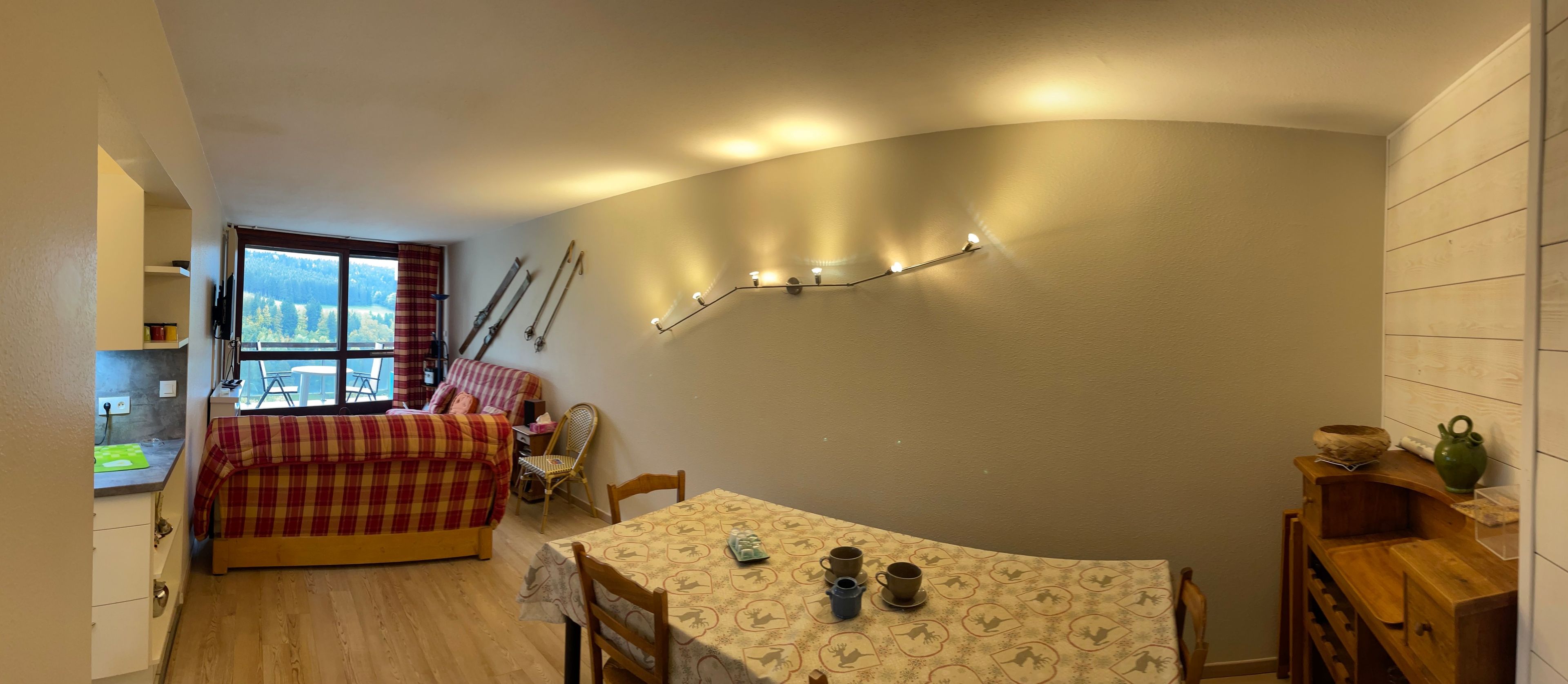 A compact room with a bed, a dining table, and a view of the outdoors.