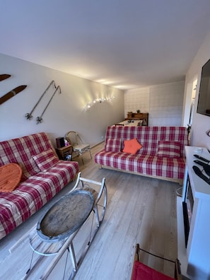 Una sala de estar acogedora con dos sofás de cuadros, una mesa de centro de madera y una zona de comedor con mesa y sillas.
