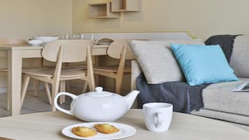 Un'area pranzo con un bollitore bianco, una tazza bianca e due pasticcini su un tavolo.
