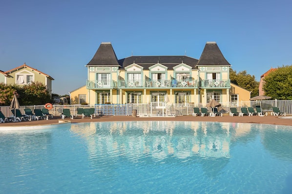 Un grand bâtiment avec une piscine devant.