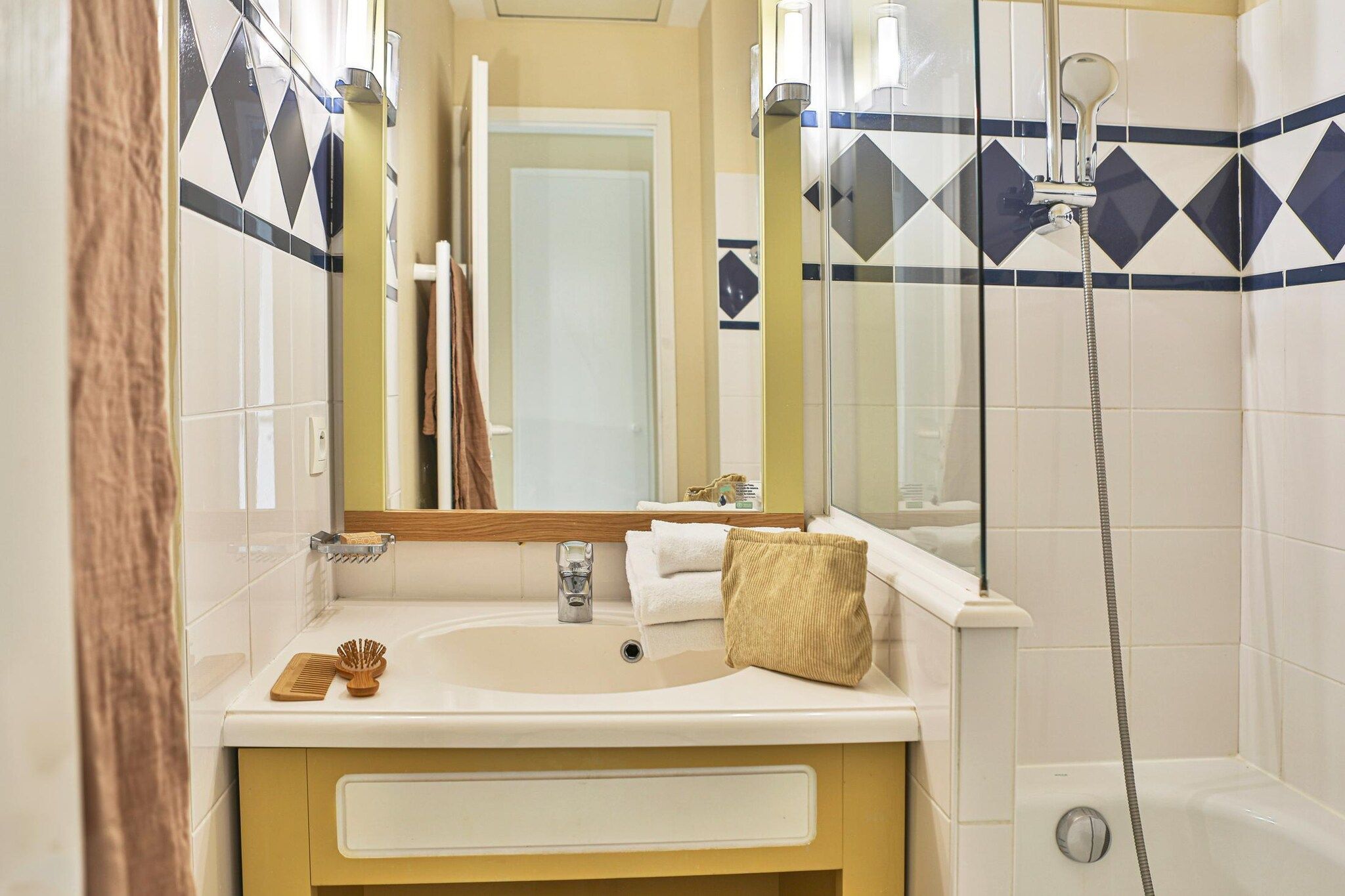 Une salle de bain équipée d’un lavabo, d’un miroir, d’un porte-serviettes et d’une douche.