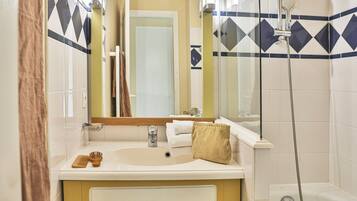 Une salle de bain équipée d’un lavabo, d’un miroir, d’un porte-serviettes et d’une douche.