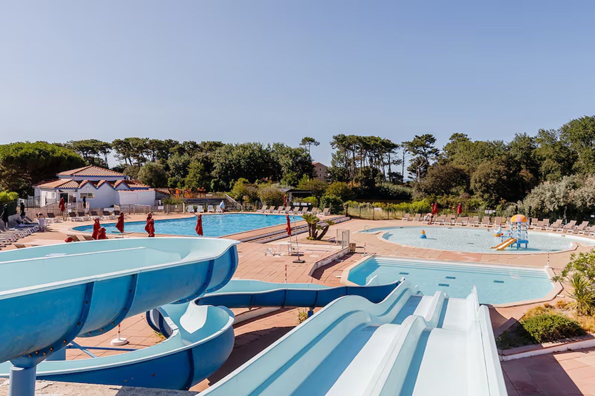 Un parc aquatique doté de nombreux toboggans et de plusieurs piscines, entouré d’arbres et de bâtiments.