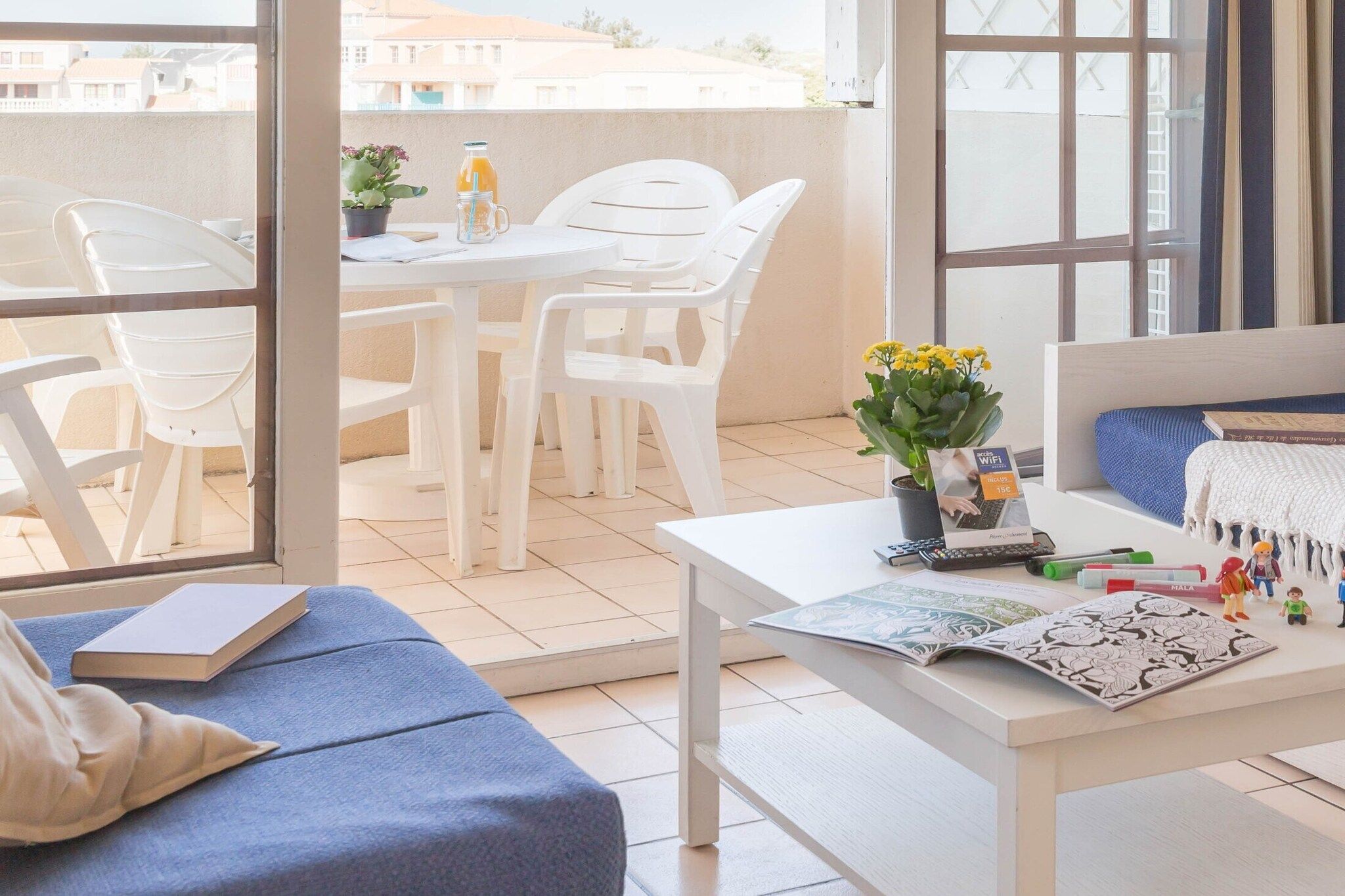 Un balcon avec une table, des chaises, un pot de fleurs et un canapé.