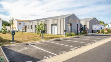 A modern building with a reception area, marked parking spaces, and a clear sky.