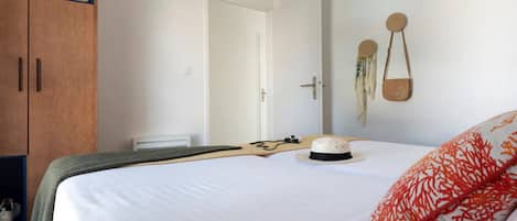 A bedroom with a bed, a wardrobe, a door, and a wall-mounted bag.