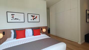 Een moderne hotelkamer met een groot bed, twee ingelijste foto's aan de muur en een kledingkast.