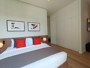 Ein modernes Hotelzimmer mit einem großen Bett, zwei gerahmten Bildern an der Wand und einem Kleiderschrank.