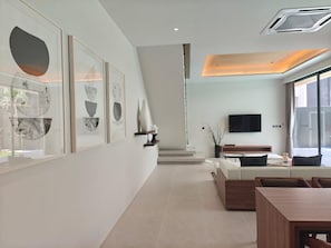 Ein modernes Hotelzimmer mit minimalistischem Design, das ein großes Fenster, einen wandmontierten Flachbildfernseher und eine Sitzecke mit einem Holztisch und Stühlen bietet.