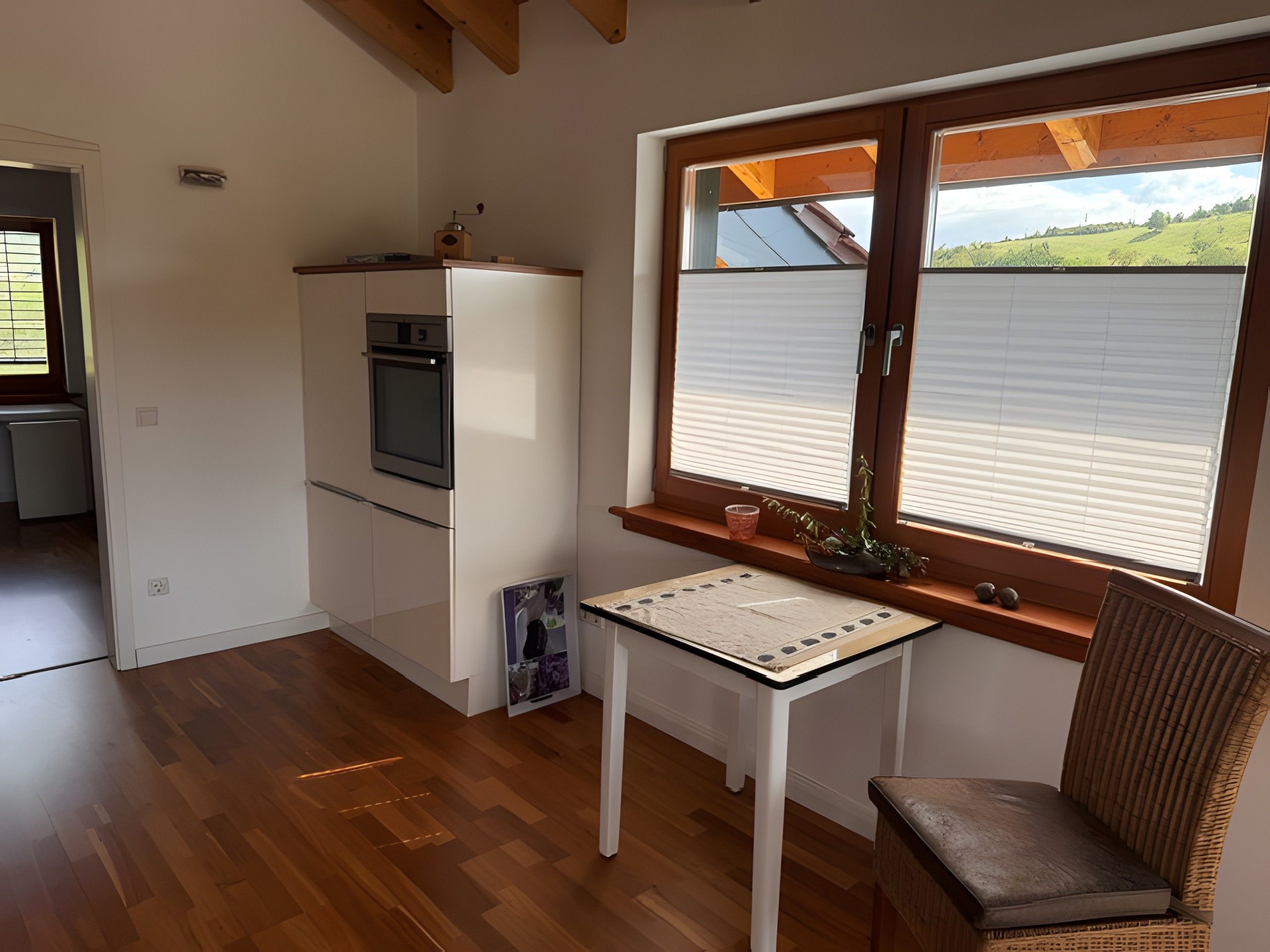 Una cocina compacta con horno empotrado y una ventana con persianas.