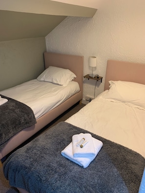 Ein Schlafzimmer mit zwei Betten, einem Nachttisch mit Lampe und einem Handtuch auf dem Boden.