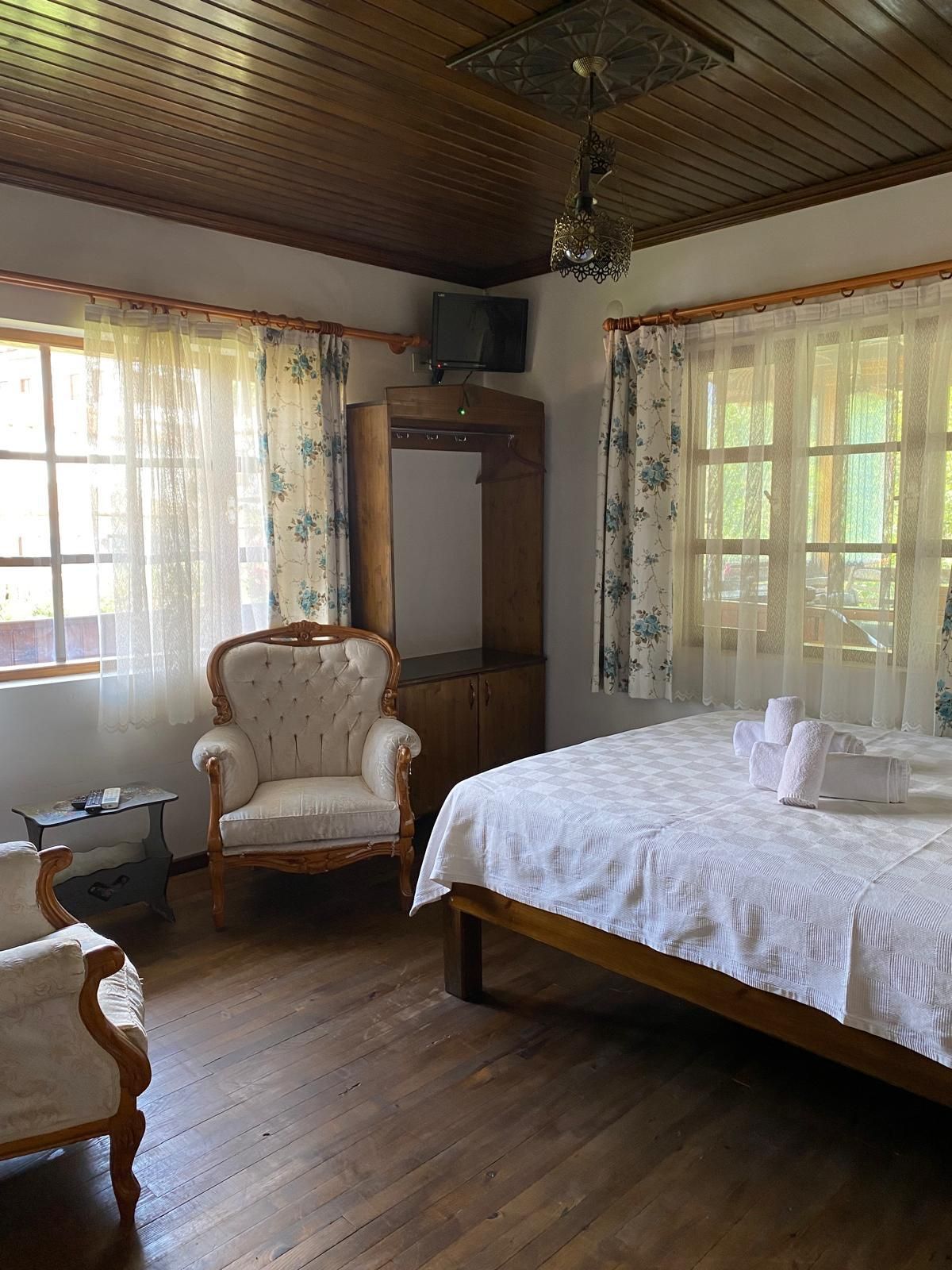 Quarto com cama, cadeira, guarda-roupa e televisão.