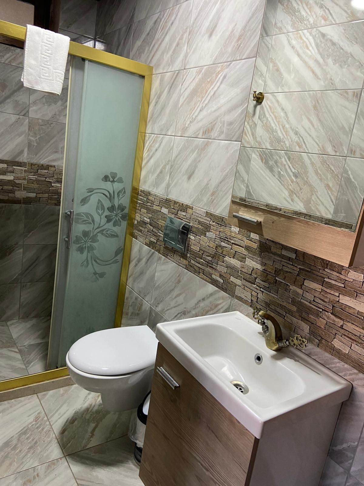 Un baño con inodoro, lavamanos y zona de ducha.