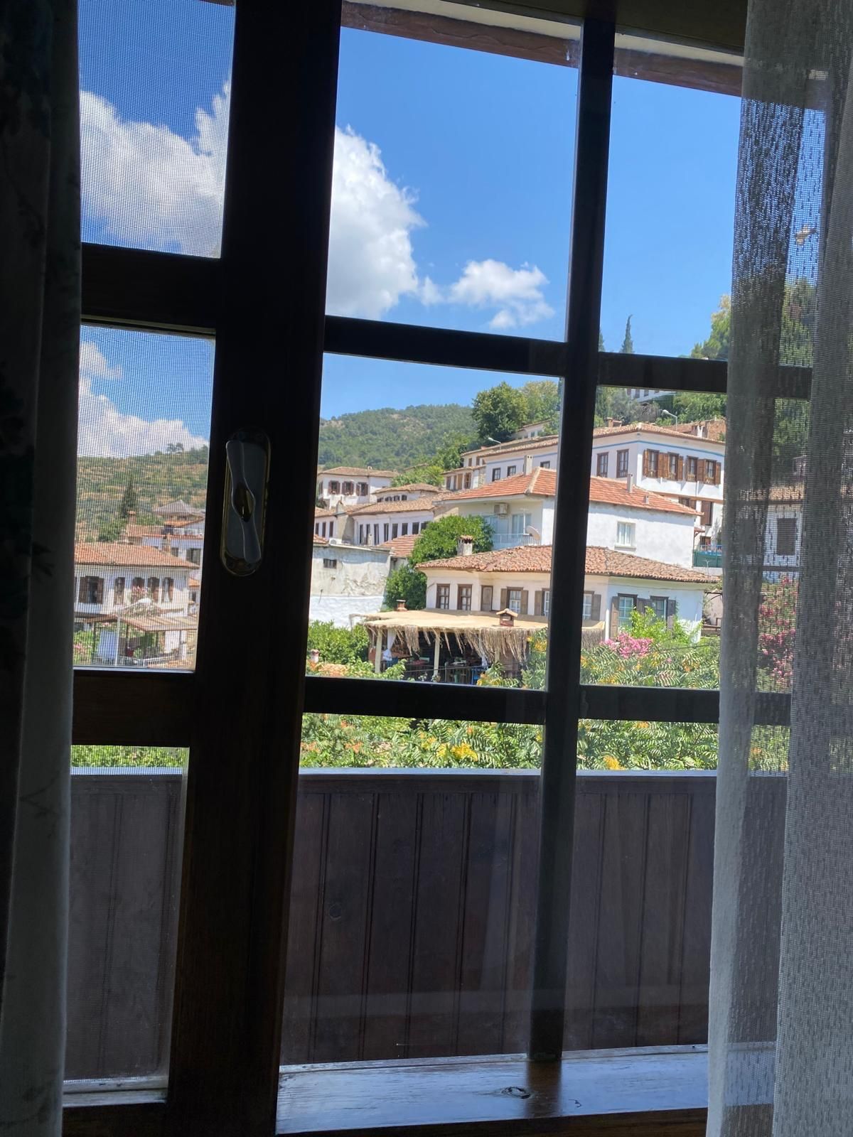 A window with a view of a hillside town with traditional buildings.