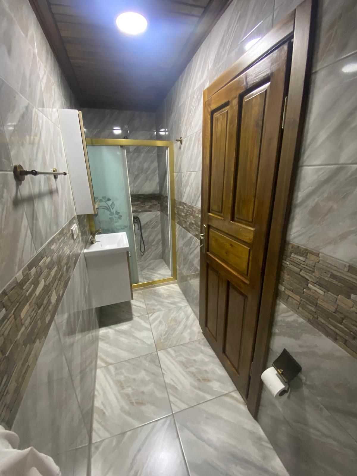 A bathroom with a toilet, a shower enclosure, and a wooden door.