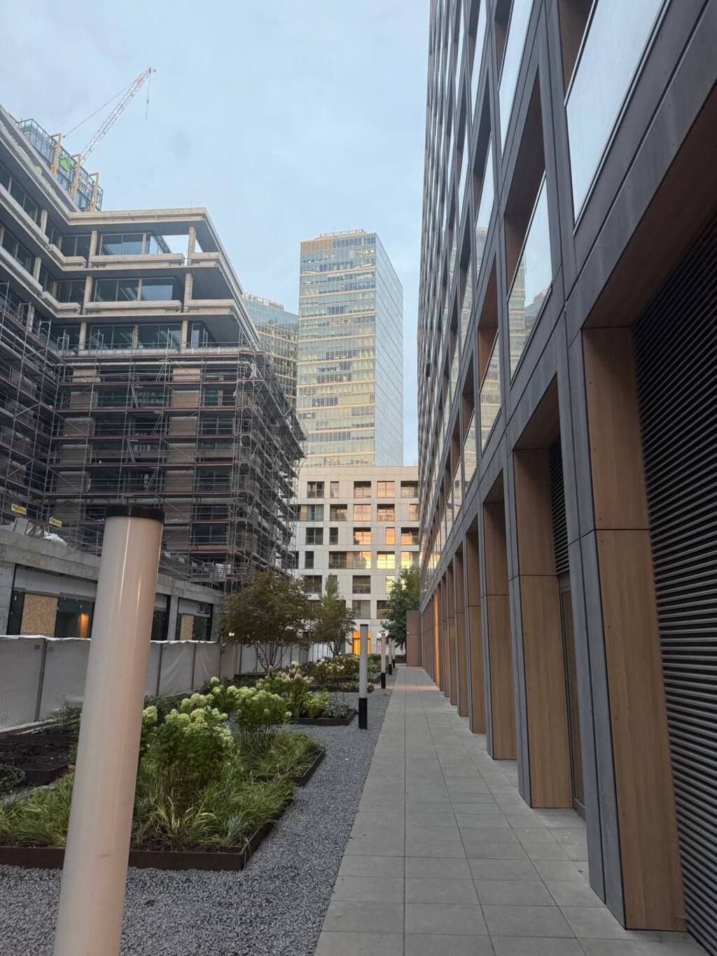 A modern building with a covered walkway and a construction site in the background.