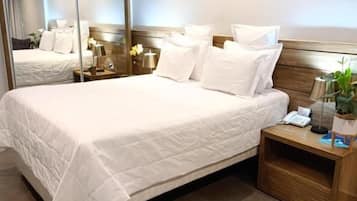 A hotel room with a large bed, a bedside table with a lamp, and a mirror.