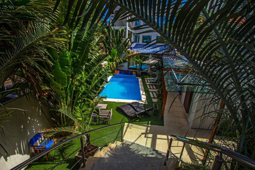 A pool area with a clear view of the pool, lounge chairs, and surrounding greenery.