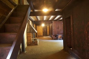 A wooden staircase leading to a room with a wooden door and a bench.