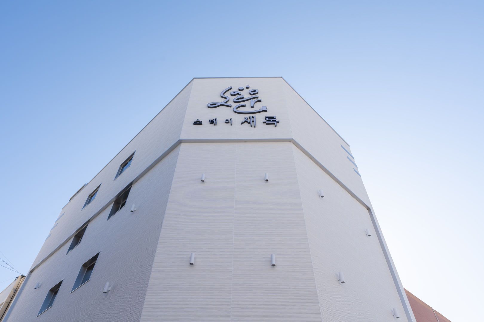 Um edifício com uma placa grande na parte superior, exibindo um logotipo e texto.