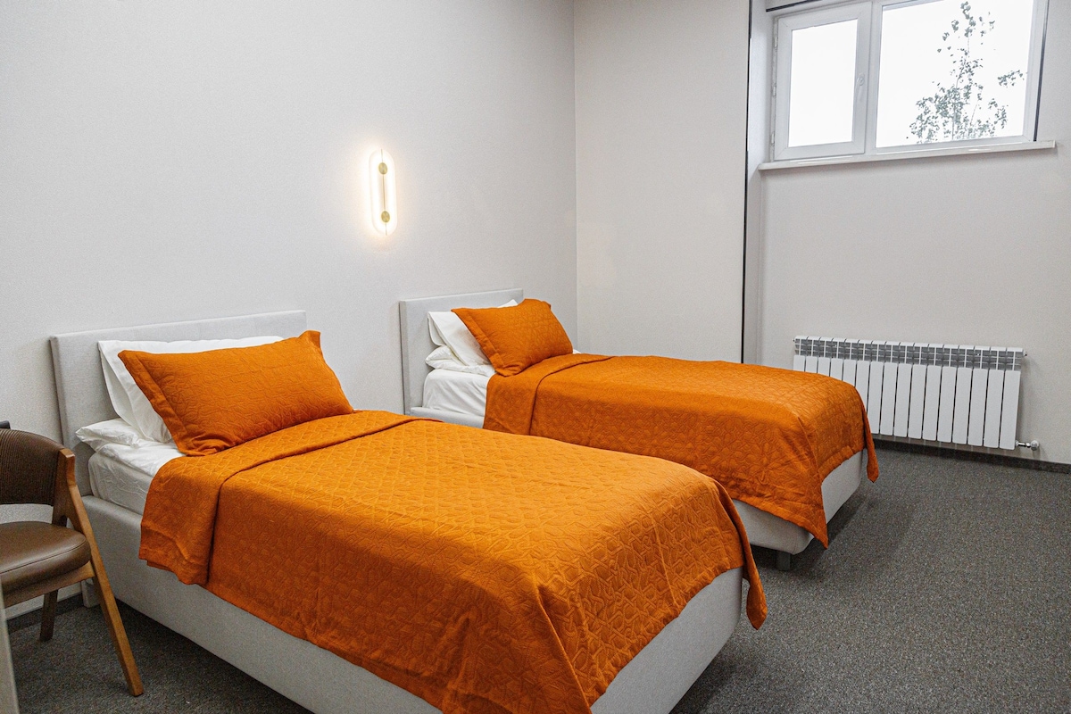 Habitación doble con dos camas, ventana y radiador.