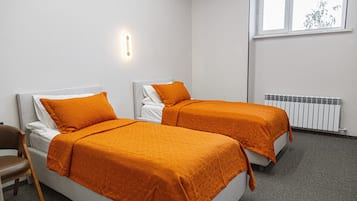 A twin room with two beds, a window, and a radiator.