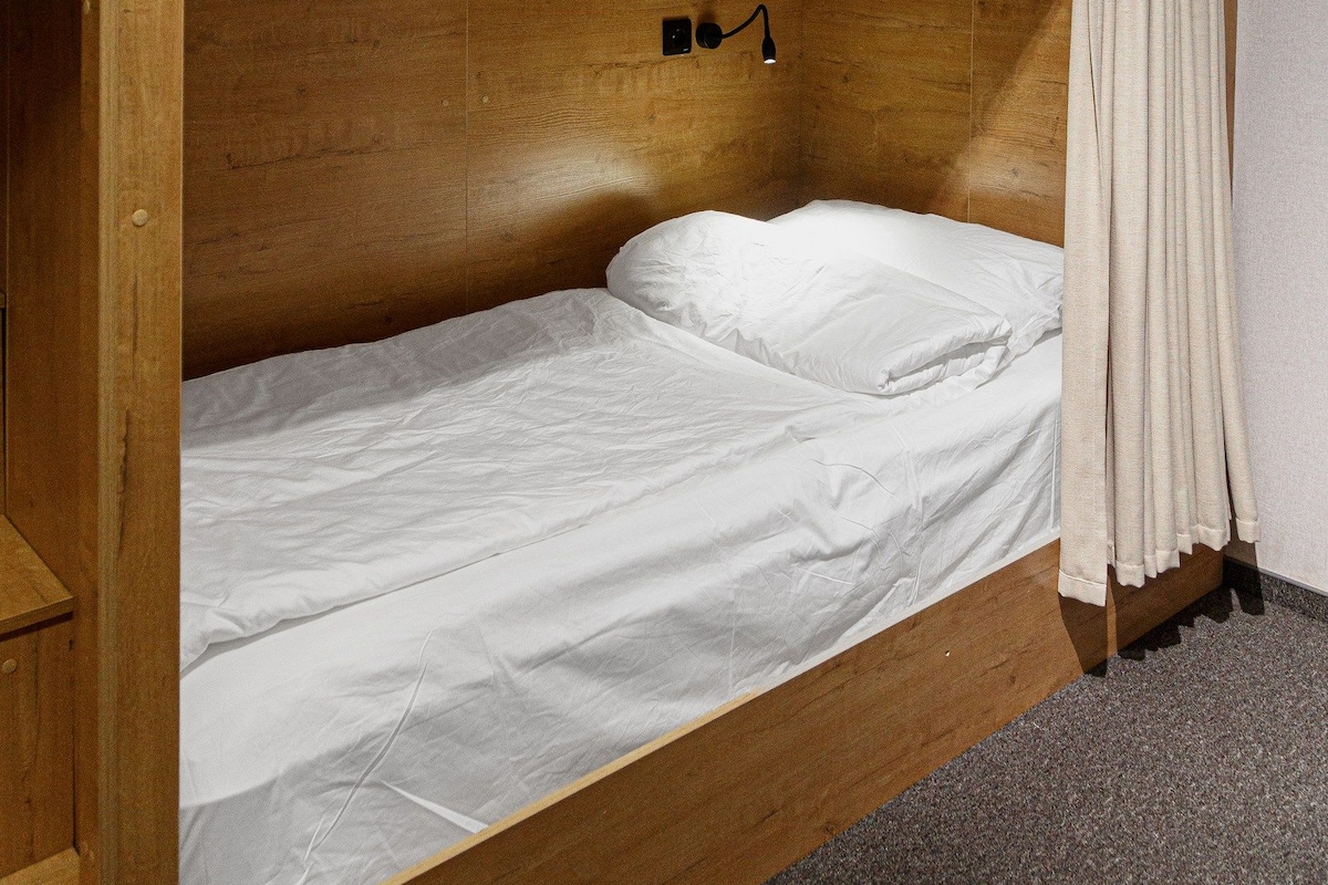 A bunk bed with a number sign, a small shelf, and a curtain.
