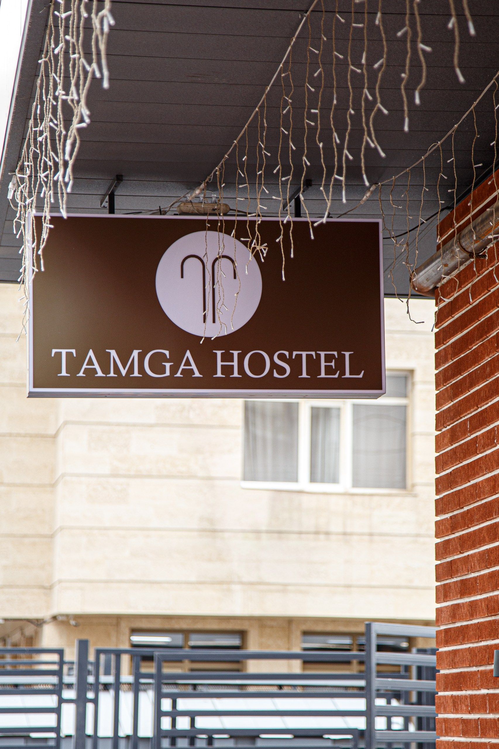 A sign for TAMGA HOSTEL with a simple, clean design.