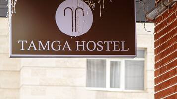 A sign for TAMGA HOSTEL with a simple, clean design.