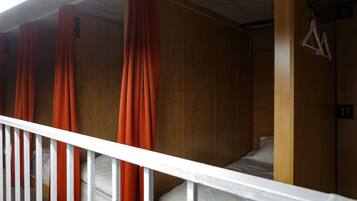 A room with a wooden floor, a white railing, and orange curtains.