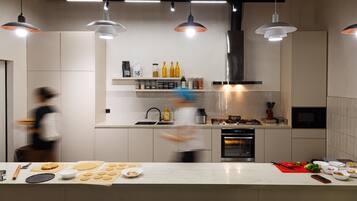 A modern kitchen with pendant lighting, a stainless steel range hood, and a variety of kitchen appliances.
