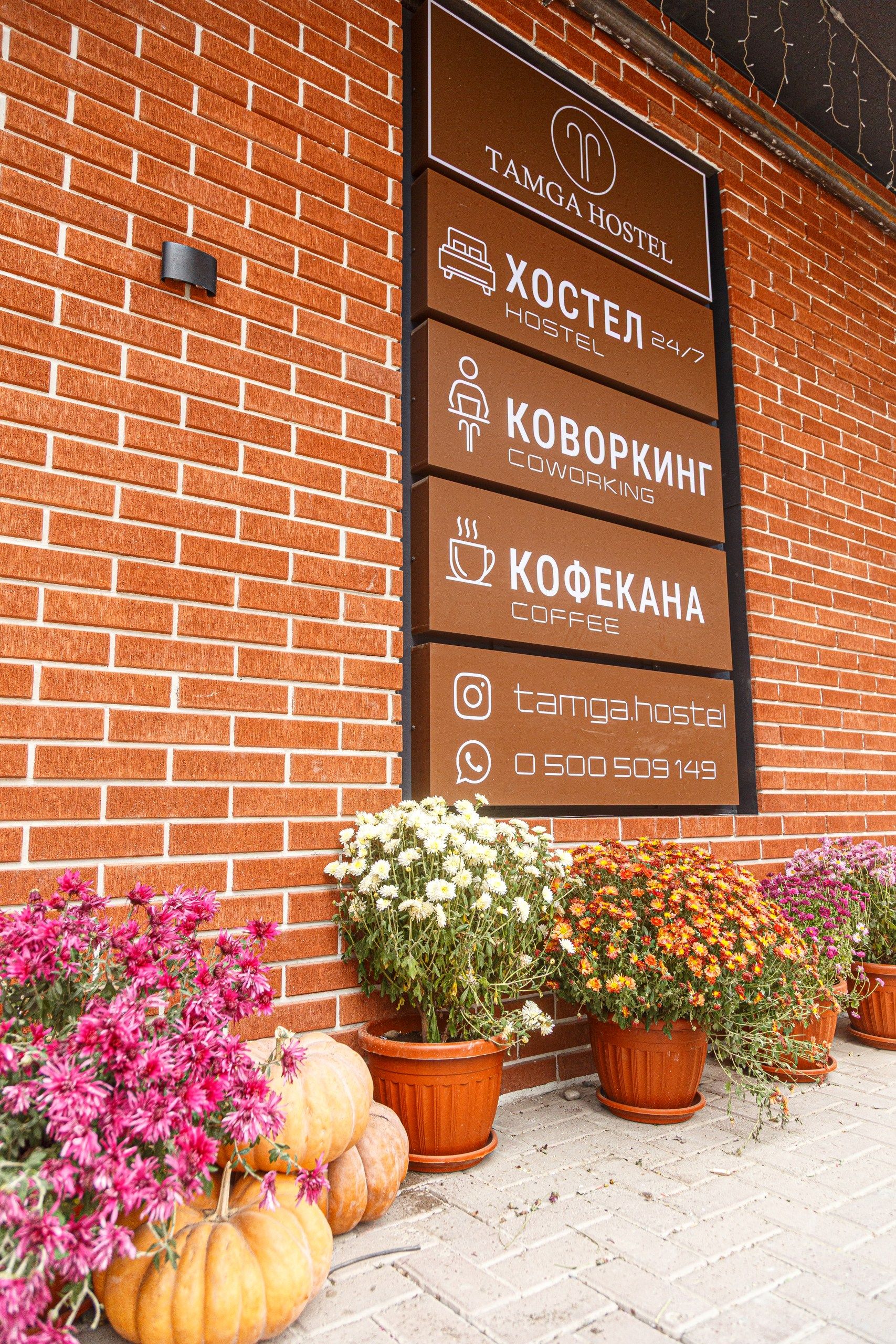 A hostel sign with amenities including a hostel, coworking space, and coffee.