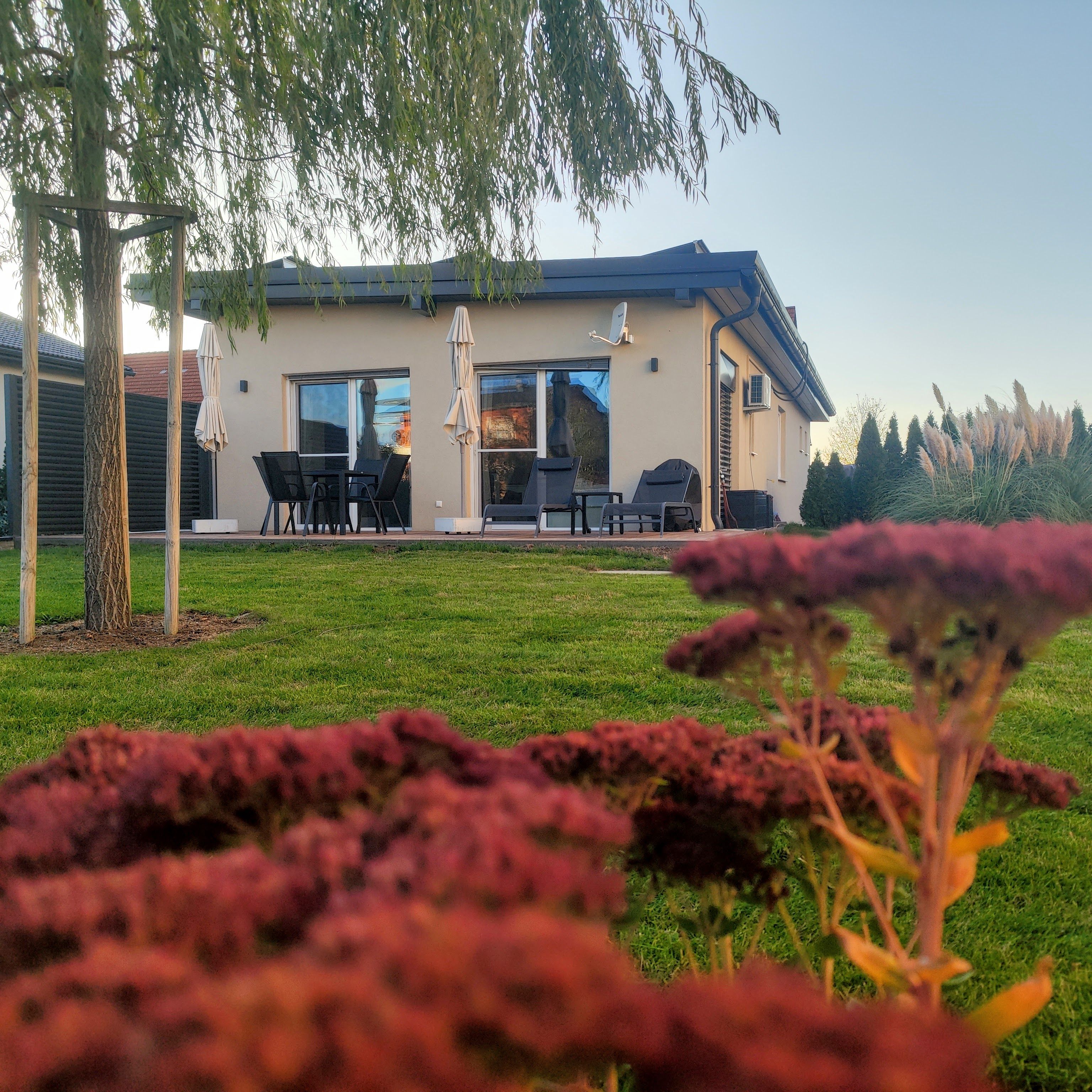 A modern house with a patio, outdoor seating, and a large window.