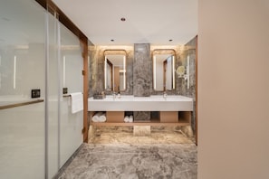 Un bagno moderno con box doccia in vetro, doppio lavabo, pavimento in marmo e scaffalature integrate.