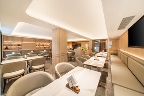 Un'accogliente hall d'hotel moderna con zone relax, tavoli e un bar.