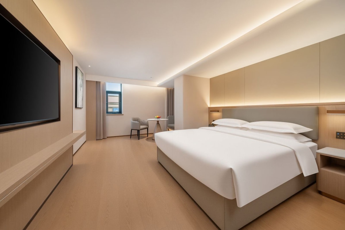 Una moderna camera d'albergo con un ampio letto, una scrivania e una televisione.