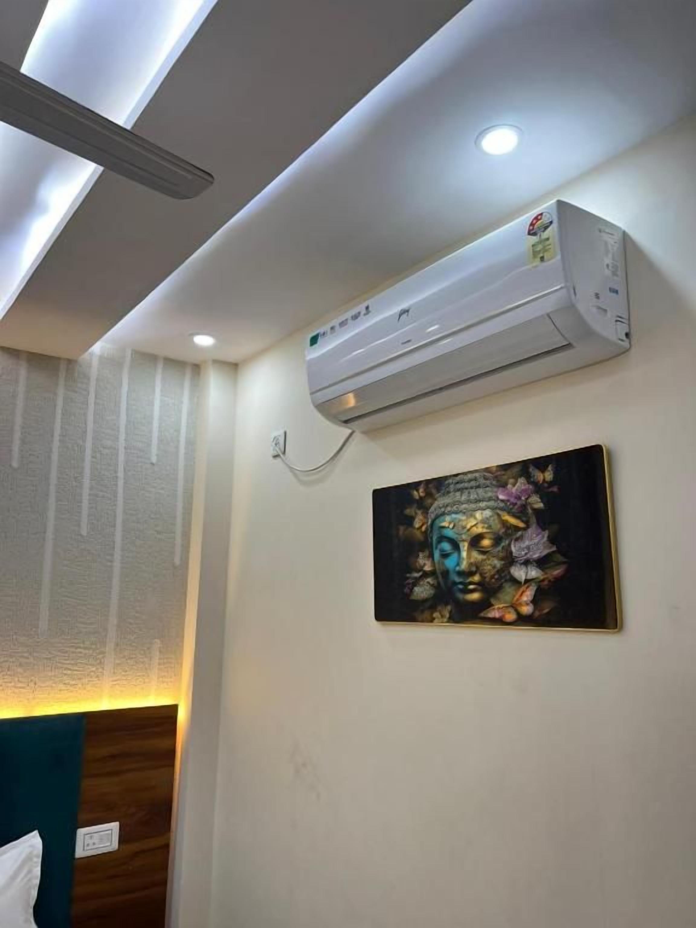 Techo con iluminación empotrada, un equipo de aire acondicionado y una obra de arte colgada en la pared.