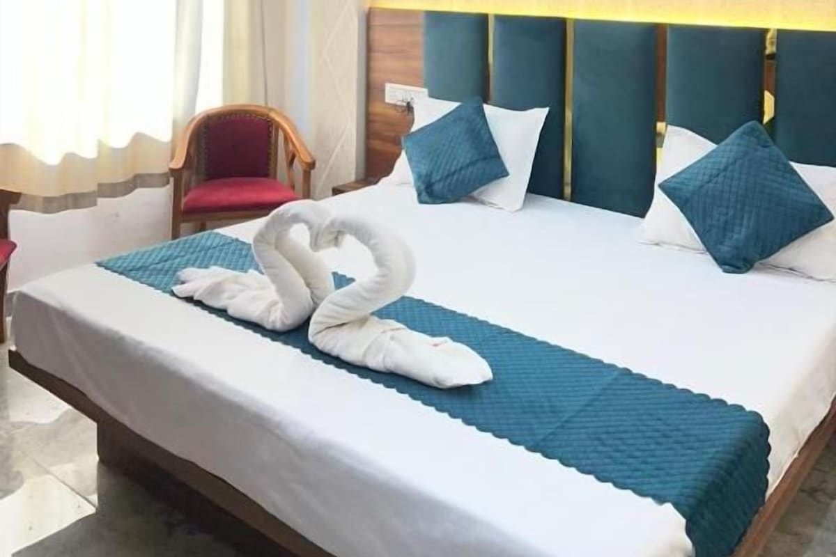 A hotel room with a bed, a headboard, a nightstand, a chair, and a ceiling fan.