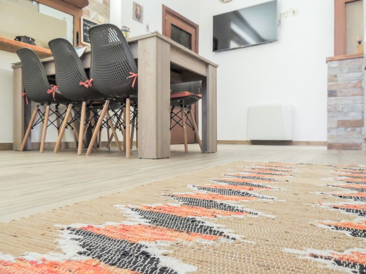 Ein Essbereich mit Tisch und Stühlen, einem gemusterten Teppich und einem Fernseher an der Wand.
