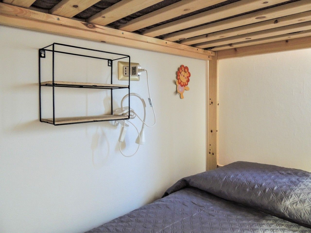 A room with a bed, a wall-mounted charging station, and a decorative item.