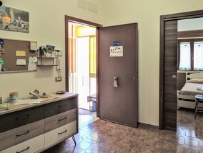 A hotel room with a bed, a bedside table, a mirror, a dresser, and a door leading to a hallway. - Porta Nord Lodge - A Historic Residence Nestled in the Castle Rock in Sperlinga (Sperlinga)