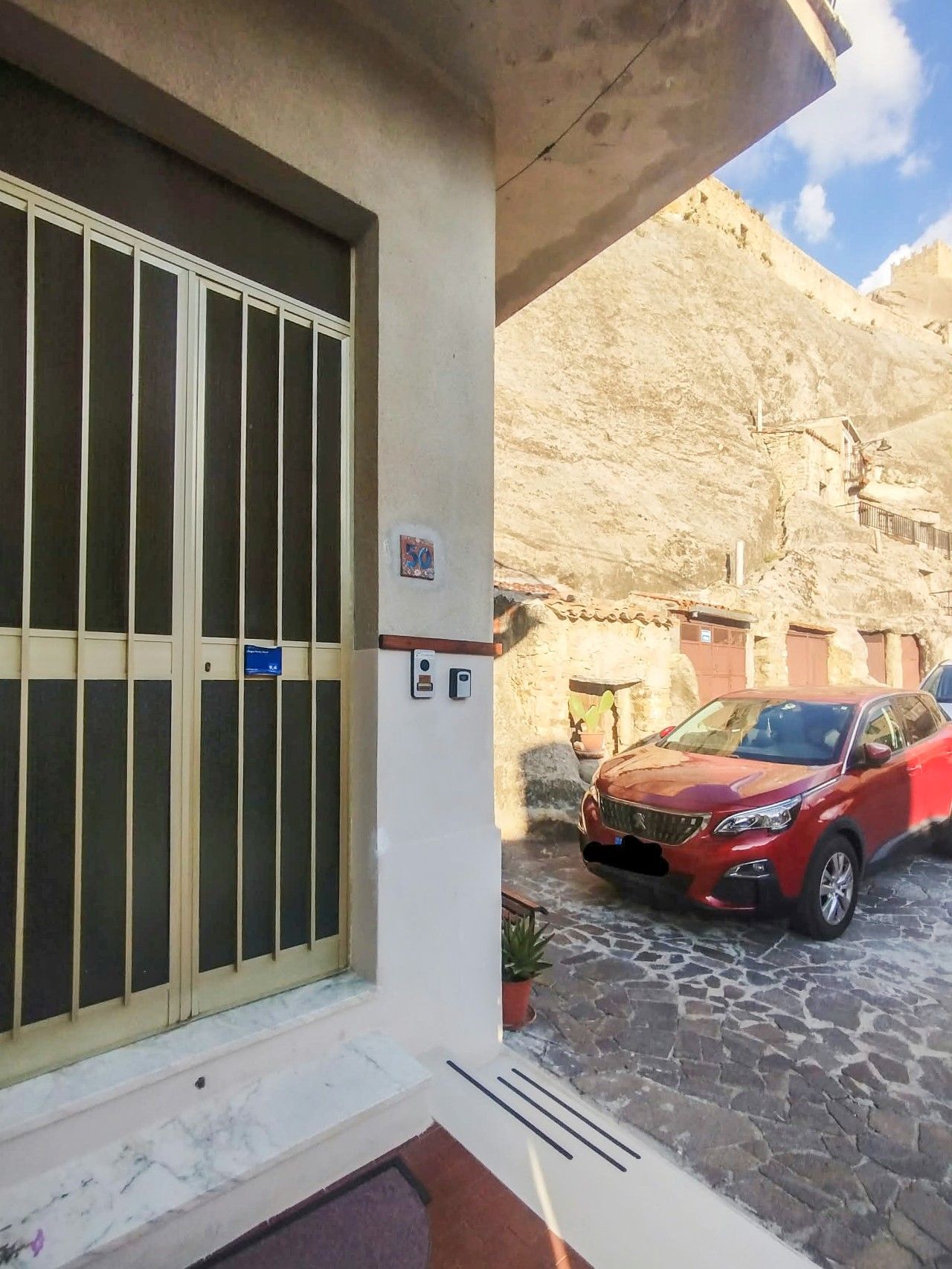 Ein Gebäude mit einem großen Fenster, einer Tür und einem kleinen Schild. Vor dem Gebäude ist ein Auto geparkt.